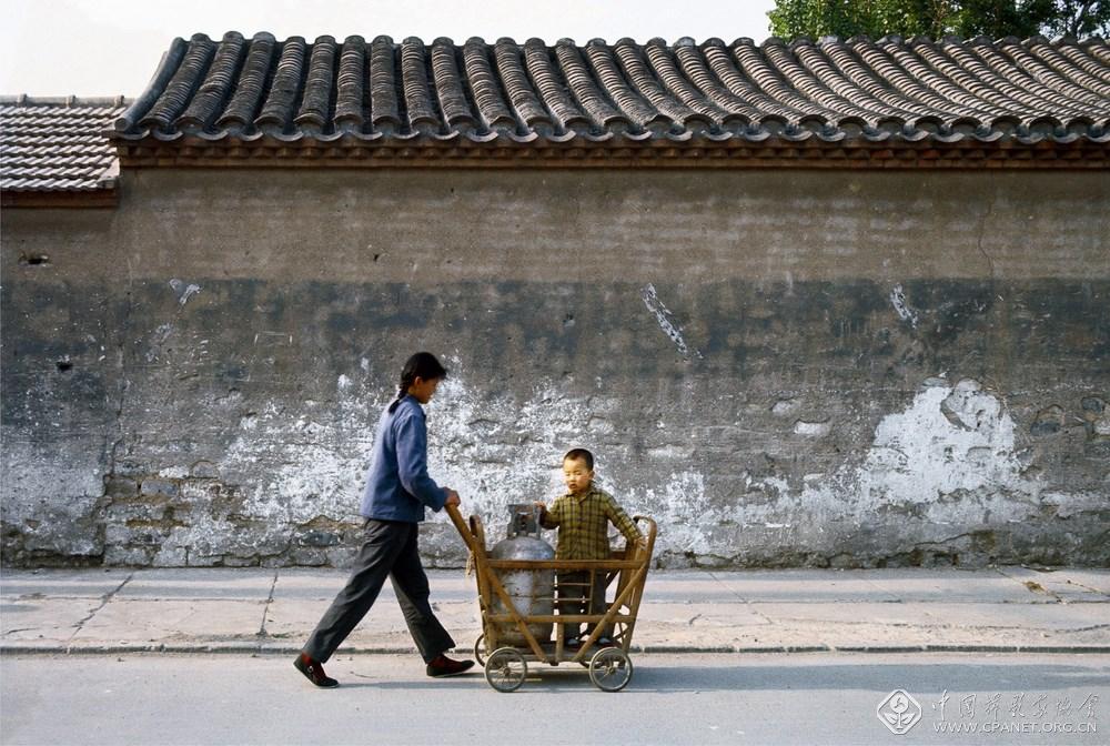 阿德里亚诺·马达罗  编号：1-04；图片说明：北京，年轻的妈妈，将孩子和煤气罐放在竹编儿童车内，推着飞快前进 (复制).jpg