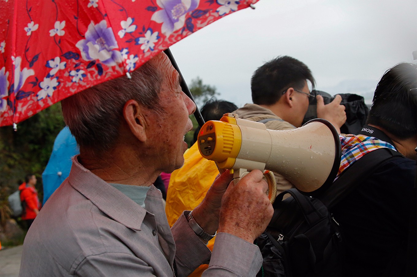 16 2014年5月15日，霞浦县松港镇北岐村，78岁老渔民出身的摄影导游欧朋飞 ，正通过手中的扩音喇叭。指挥着海边渔民配合拍摄。老人转行干摄影导游已有4年多。 .jpg